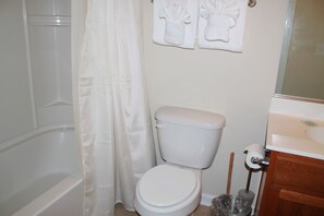 A bathroom with a toilet, a shower curtain, and a sink.