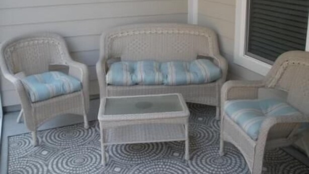Un rincón amoblado con muebles de mimbre y un tapete estampado.