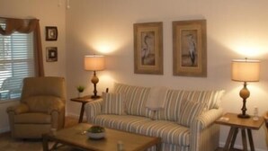 Una sala de estar con un sofá a rayas, una mesa de centro de madera, un sillón y dos lámparas.