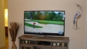 Un televisor montado en un soporte de madera con un reloj y objetos decorativos.