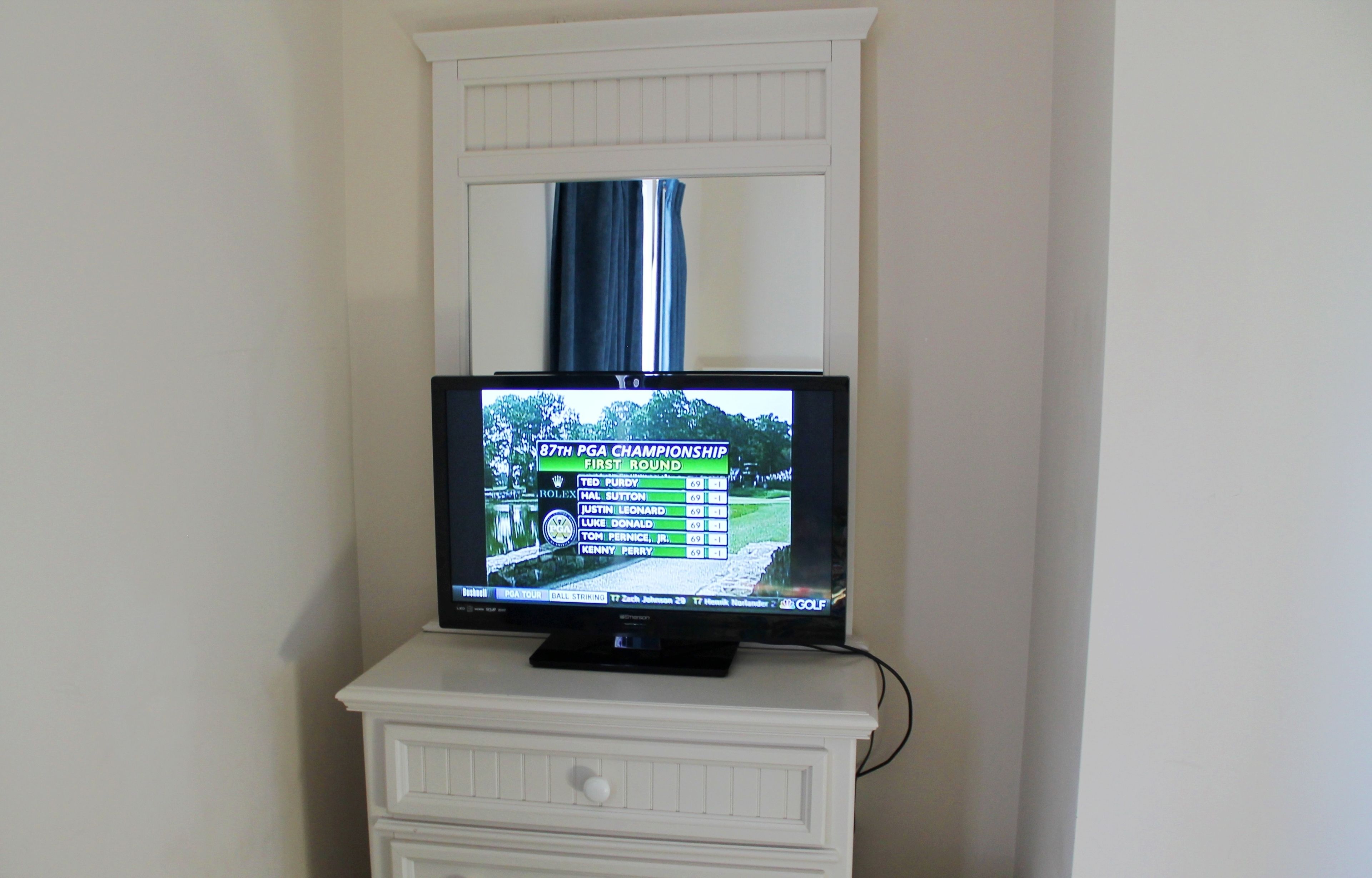 A television displaying the 87th PGA Championship first round scores.