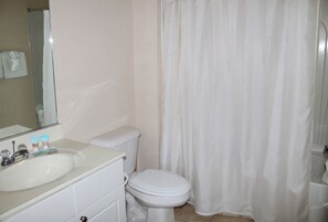 A bathroom with a white sink, mirror, and toilet.