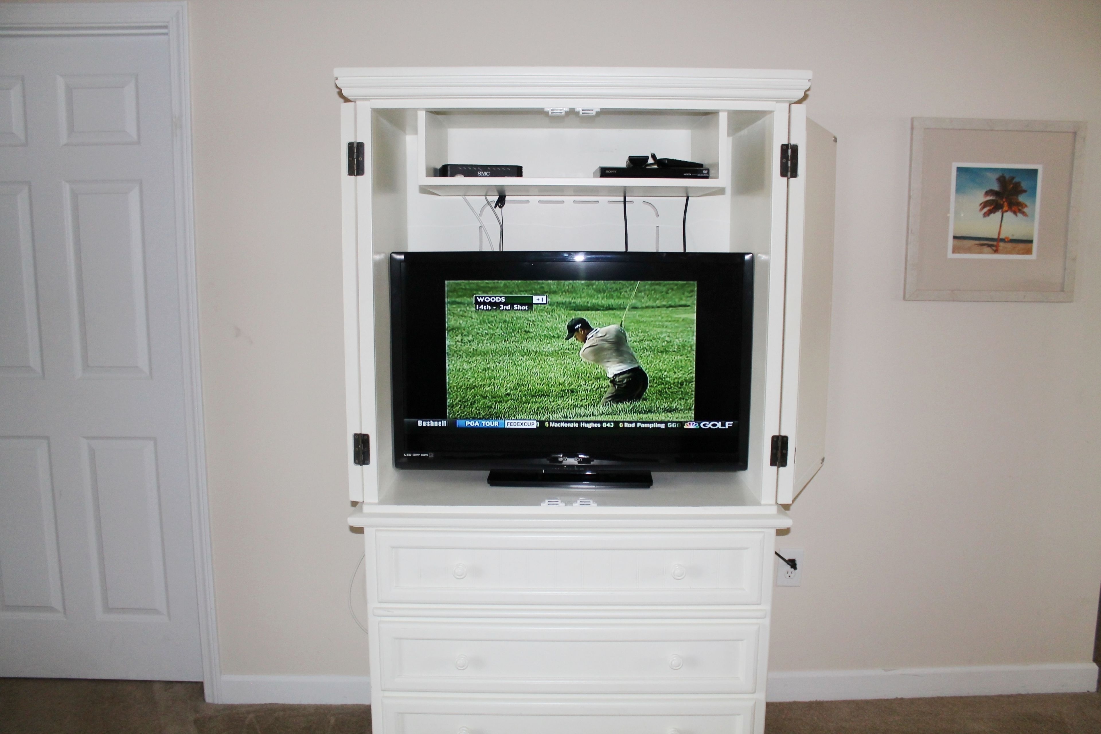 A television on a white entertainment center with a shelf above it.
