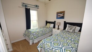 A bedroom with two beds, a ceiling fan, a window with curtains, a bedside table with a lamp, and a painting on the wall. - 1715 Willow Bend (North Myrtle Beach)