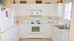 A kitchen with white cabinets, a microwave, stove, and a sink. - 1523 The Havens (North Myrtle Beach)