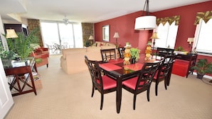 A dining area with a table and chairs, a sofa, and a balcony with chairs. - 1805 Yacht Club Villas (North Myrtle Beach)