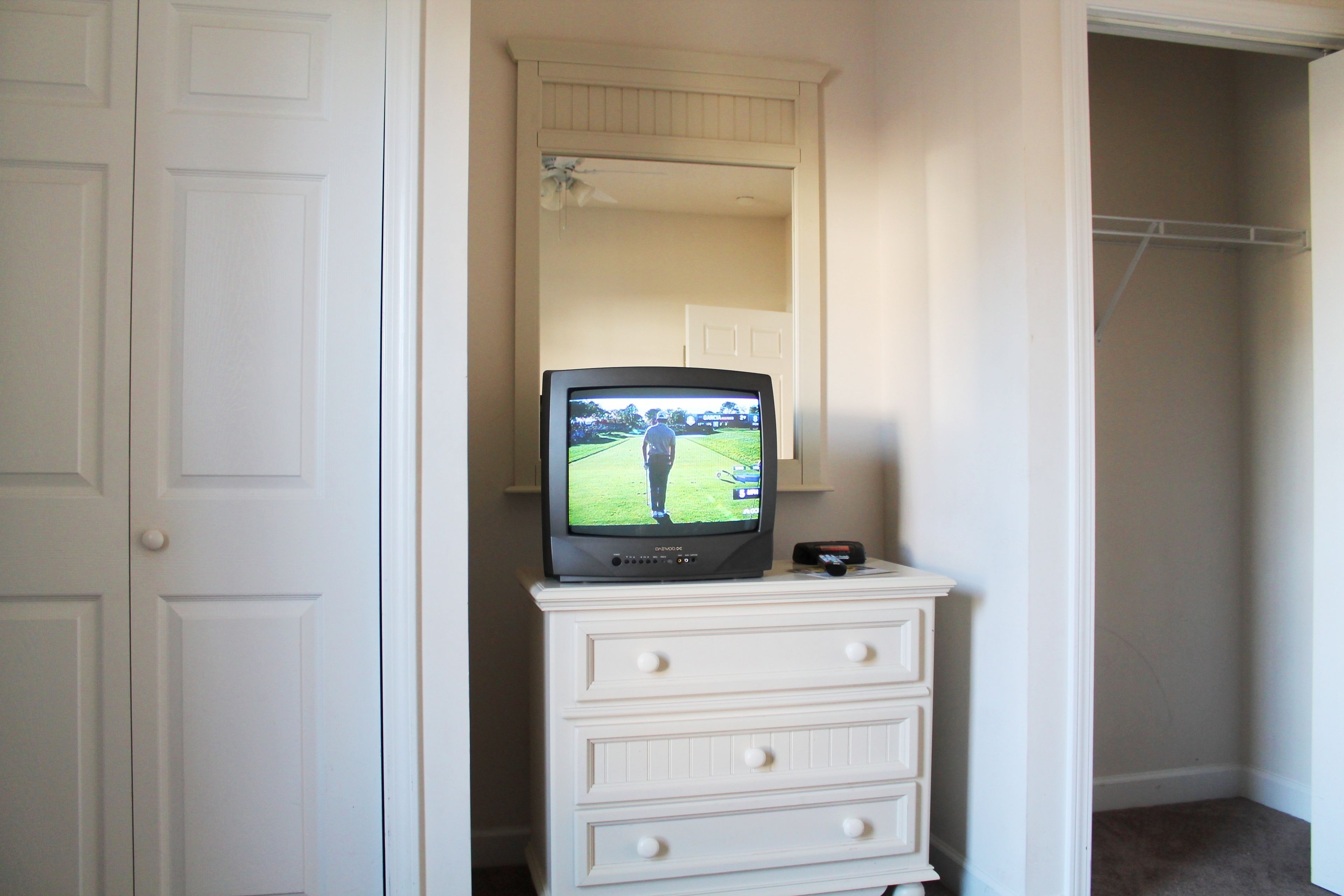 A white dresser with a television on top.