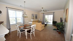 A dining area with a table and chairs, a sofa, and a ceiling fan. - 411 Willow Bend (North Myrtle Beach)