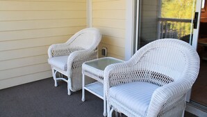 Ein weißer Korbstuhl und ein Tisch auf einer Veranda mit einer Schiebetür.