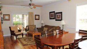 A spacious living room with a wooden dining table, comfortable seating, and a ceiling fan. - 614 Willow Bend (North Myrtle Beach)