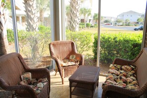 Enjoy a peaceful retreat with a view of the surrounding neighborhood from this cozy room, featuring a large glass door leading to an outdoor area with wicker furniture.