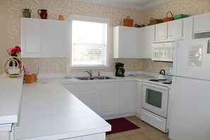 Enjoy cooking in this kitchen with oven and refrigerator, featuring a window with blinds and patterned wallpaper.
