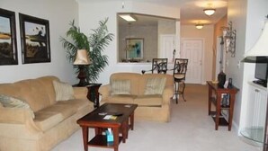A living room with a beige sofa, a coffee table, and a TV stand. - 734 The Havens (North Myrtle Beach)