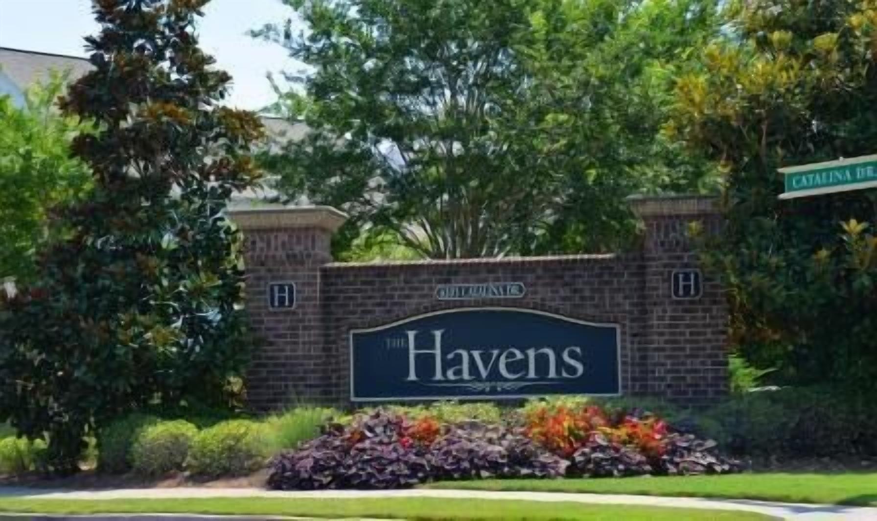 Un muro de ladrillo con un cartel que dice "The Havens" y una señal de calle que indica "Catawissa Drive".