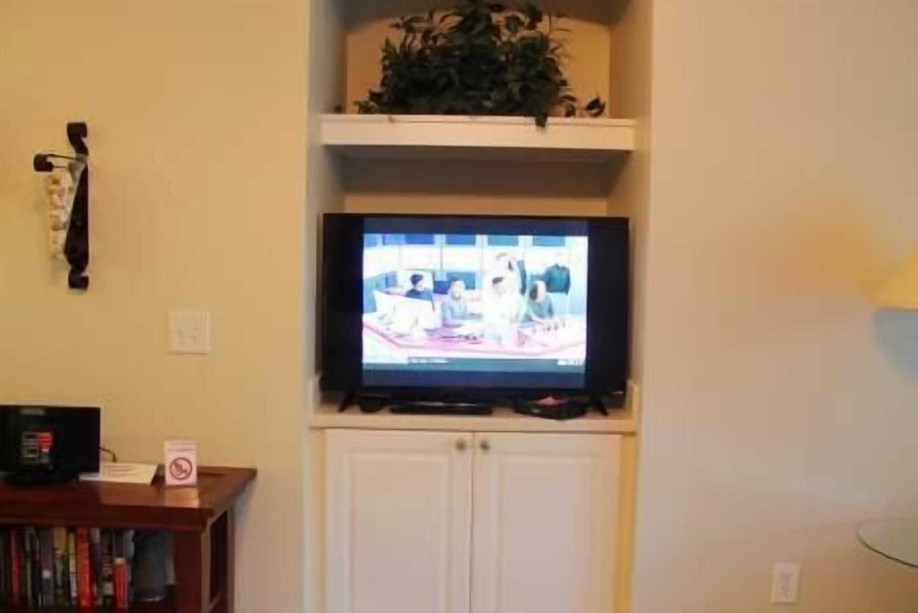 Un televisor sobre un soporte en una habitación con un mueble blanco debajo.