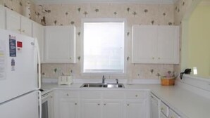 A kitchen with white cabinets, a window above the sink, and a toaster on the counter. - 1321 The Havens (North Myrtle Beach)