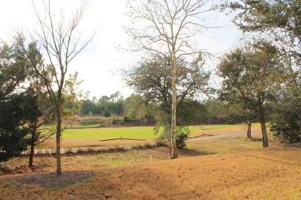 A golf course with trees, a fence, and a clear sky. - 1212 The Havens (North Myrtle Beach)
