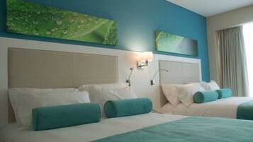 Habitación de hotel con dos camas, ropa de cama color turquesa, un ventanal con cortinas y una obra de arte en la pared.