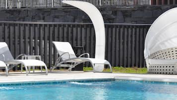 Una piscina techada, una piscina al aire libre, sombrillas