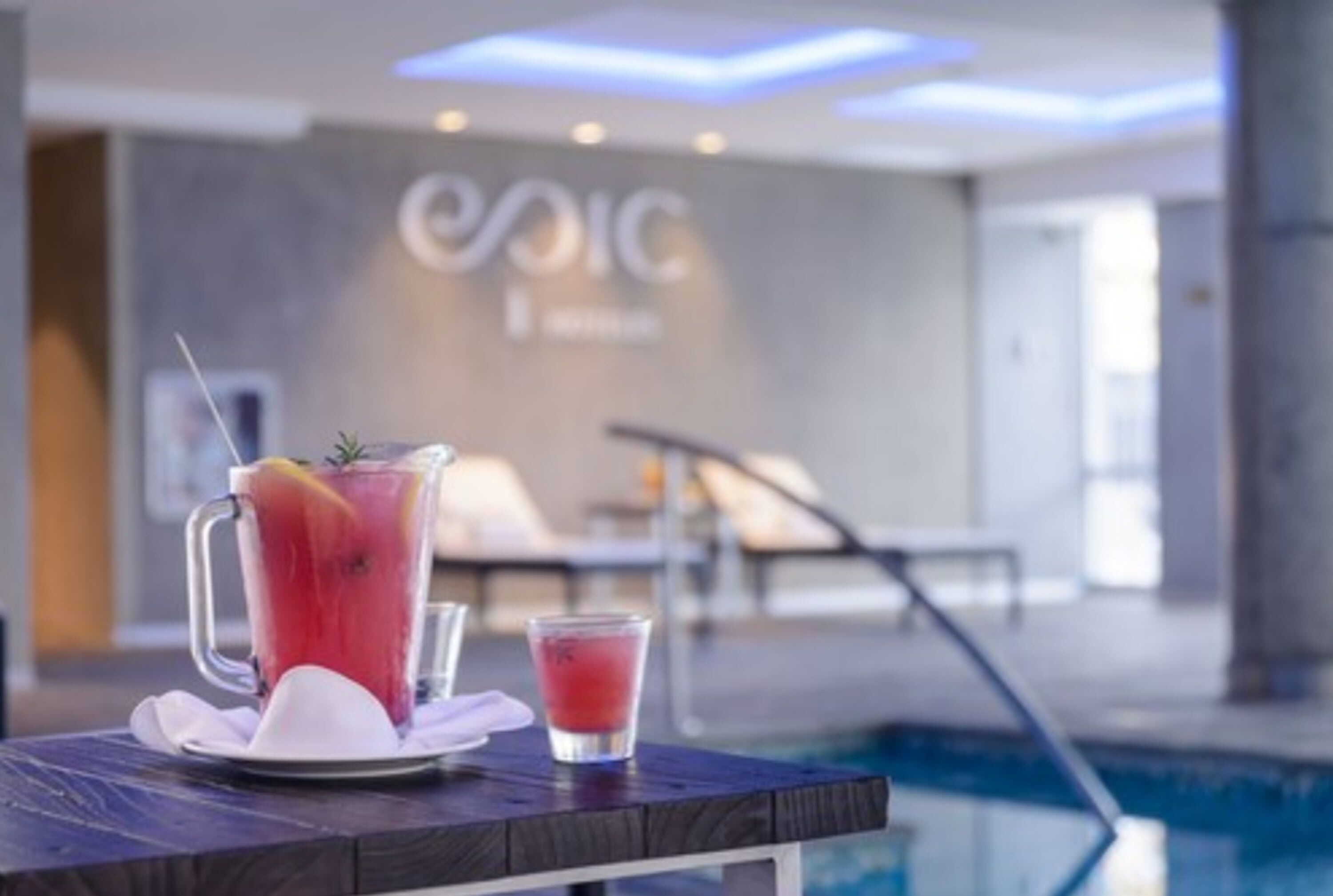 Zona de piscina con una bebida, una silla de descanso y una pared con el texto "EPCIC".