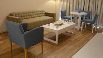 Una sala de estar moderna con un sofá beige, sillones azules, una mesita de centro blanca y una pequeña mesa redonda con sillas.