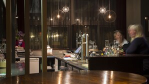 A bar area with a counter, bar stools, and hanging pendant lights. - The Cinema Suites (Te Anau)