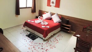 Una habitación de hotel con una cama, una mesita, una silla y una ventana con cortinas.