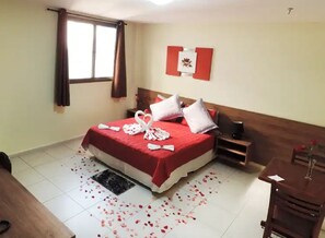 Una habitación de hotel con una cama, una mesita, una silla y una ventana con cortinas.