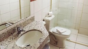 Un baño con lavamanos, inodoro y ducha.