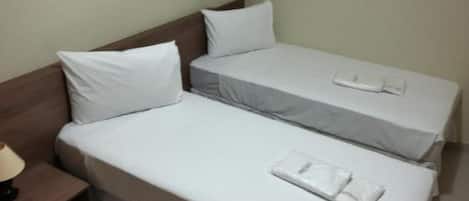 Una habitación de hotel con dos camas individuales, una mesita de noche y un cuadro enmarcado en la pared.