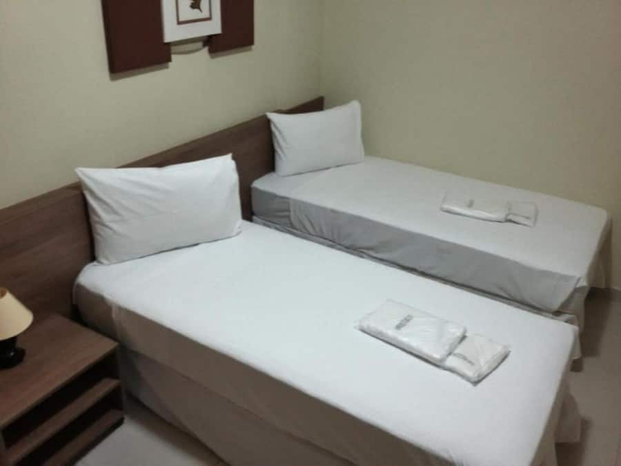 A hotel room with two single beds, a nightstand, and a framed picture on the wall.