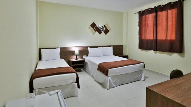 Habitación de hotel con dos camas, un escritorio y una obra de arte en la pared.