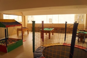 Zona de juegos con piscina de pelotas, trampolín y mesa de billar.