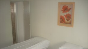 A room with two beds, one with a white bedspread and the other with a white blanket. There is a painting of flowers on the wall. - Pousada Mar e Sol (Recife)