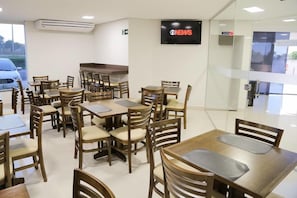 Un restaurant doté de nombreuses tables et chaises, d’un téléviseur à écran plat fixé au mur et d’un appareil de climatisation.