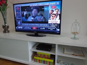 Un televisor mostrando un canal de noticias con un evento UFC visible y un libro en una estantería.