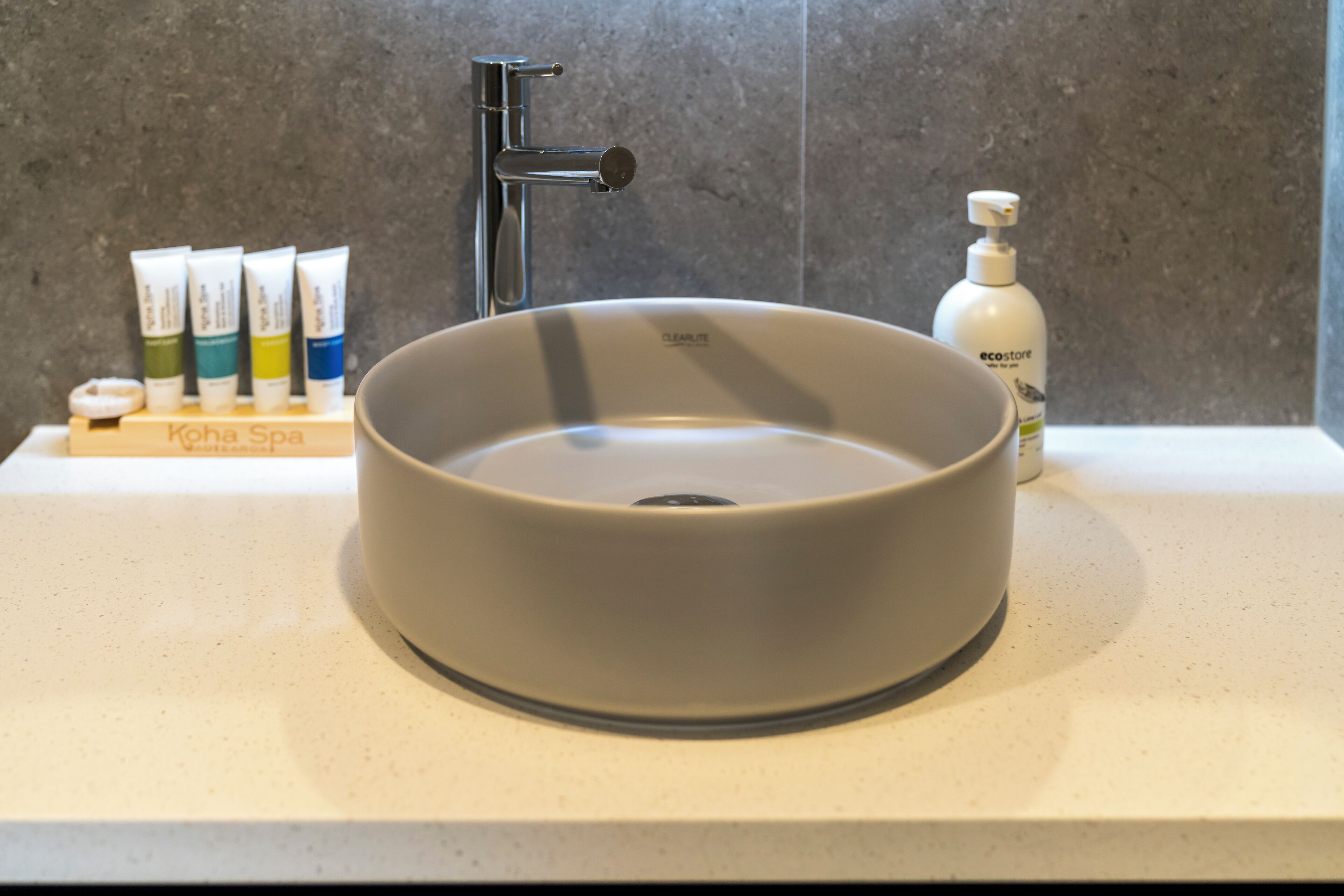Un lavabo de baño con una pileta redonda, una llave de agua y un dispensador de jabón.