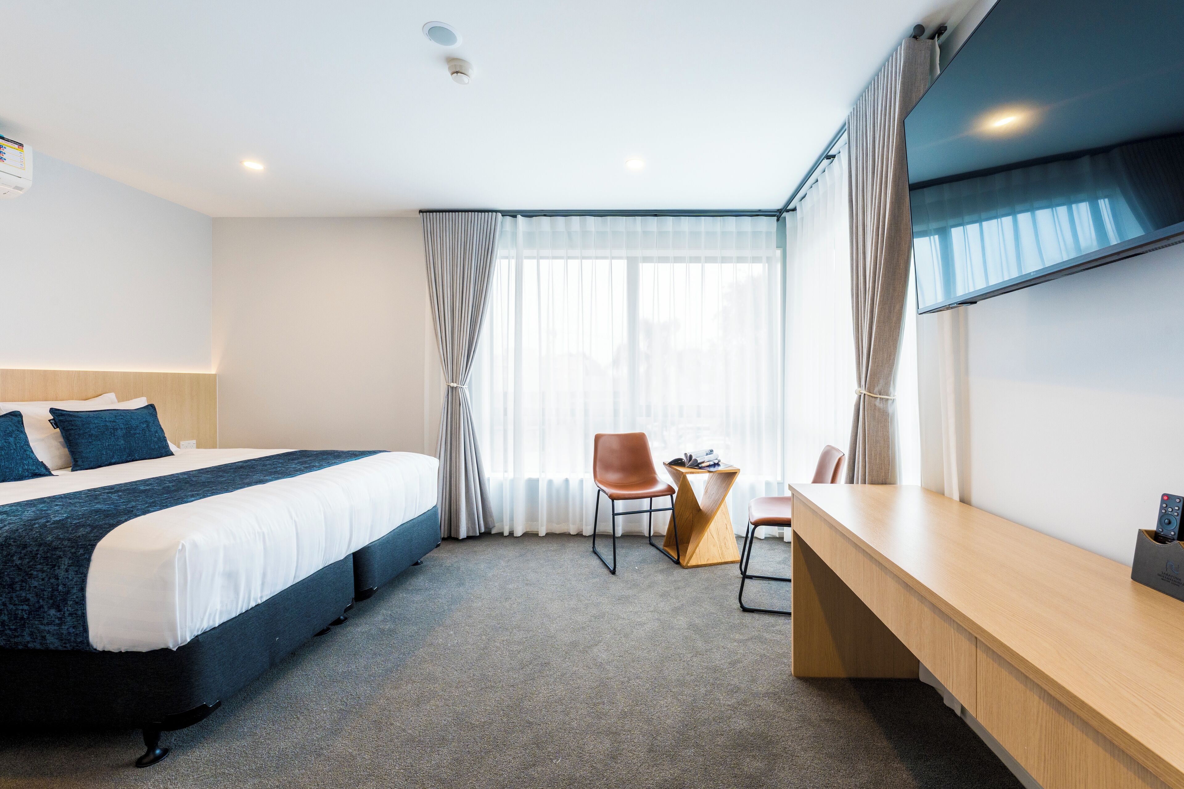 A hotel room with a bed, a desk, and a chair.