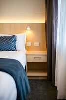 Una habitación de hotel con cama, mesita de noche y lámpara.
