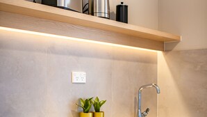 A modern kitchen with a built-in microwave, a stainless steel toaster, and a sink. There are two potted plants on the countertop. - Takapuna International Motor Lodge (Auckland)
