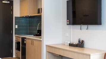 Una cocina moderna con armarios de madera, microondas integrado y televisor negro montado en la pared.