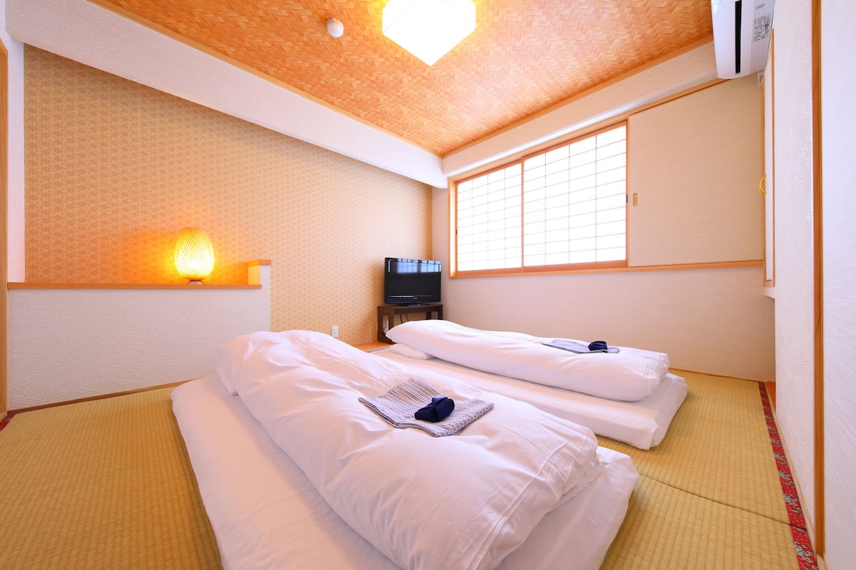 A hotel room with two beds, a TV, and a window with a view.
