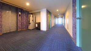 A long, narrow hallway with patterned walls and carpeted floors, leading to a door on the right. - Business Hotel Star (Beppu)
