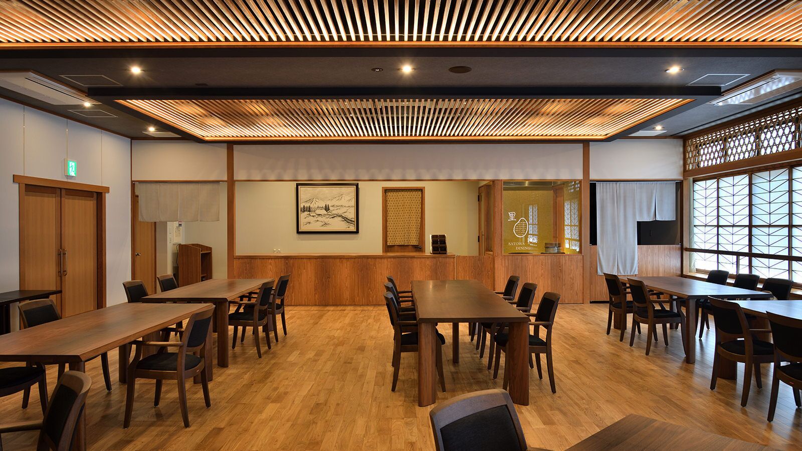 A conference room with wooden tables and chairs, a wooden ceiling with slats, framed artwork on the walls, and a view through a window with a lattice design.