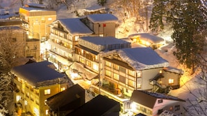 A snow-covered hotel with multiple buildings, including a main building with a balcony and several smaller structures. - Hinanoyado Chitose (Tokamachi)