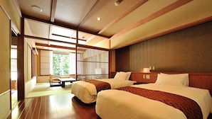 A hotel room with two beds, wooden flooring, a traditional sliding door, and a view of greenery outside. - Hinanoyado Chitose (Tokamachi)
