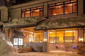 A traditional Japanese building with a snow-covered entrance and a signboard.