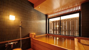 A traditional Japanese onsen with a wooden interior, a wooden toilet, and a large hot spring bath. - Hinanoyado Chitose (Tokamachi)