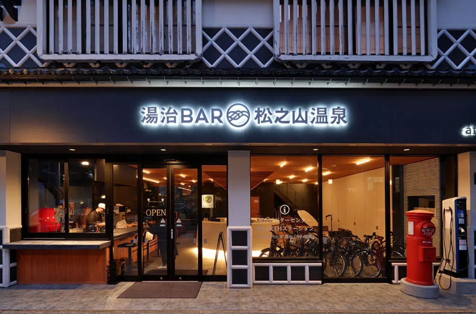 A bar with a modern design, featuring a glass door entrance and a bicycle parked outside.