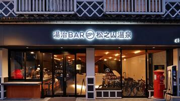 A bar with a modern design, featuring a glass door entrance and a bicycle parked outside.